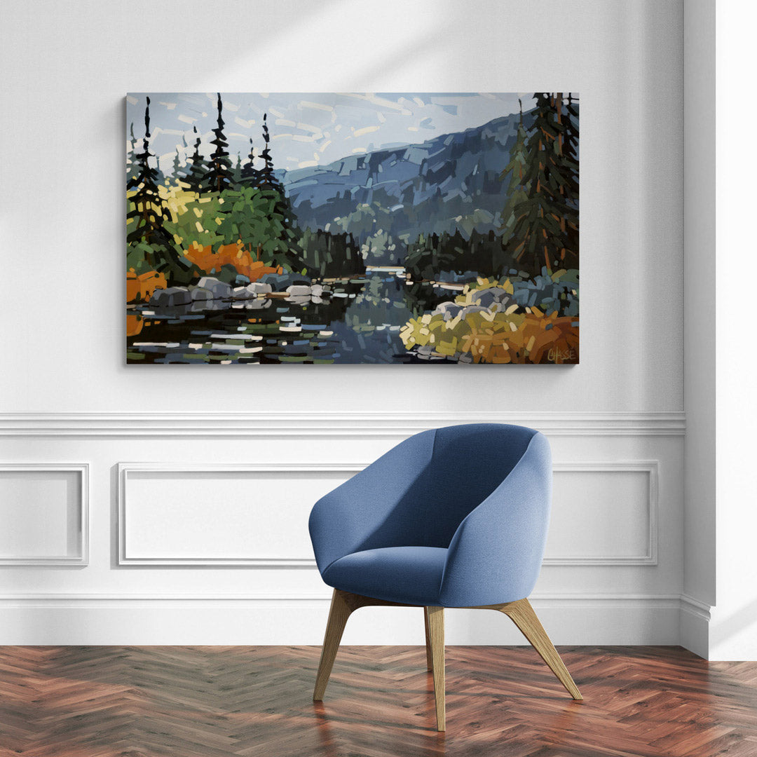 grande peinture de l'artiste peintre Martine Chassé représentant une forêt boréale avec un lac et des montagnes, présentée dans une pièce épurée avec un fauteuil bleu comptemporain.