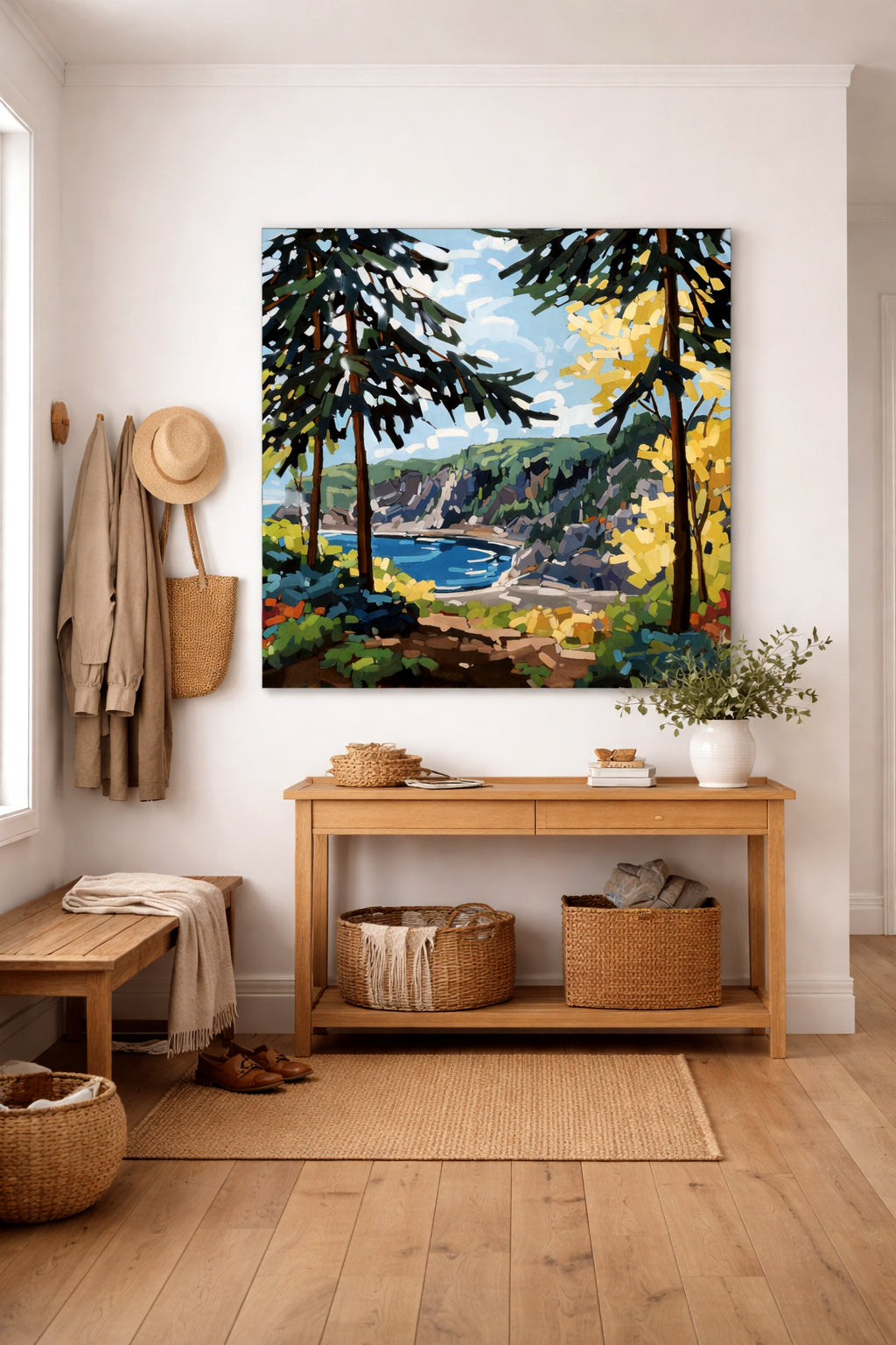 Grande peinture carrée sans cadre représentant un paysage côtier, installée dans un hall d’entrée de style scandinave avec mobilier en bois clair et ambiance épurée.