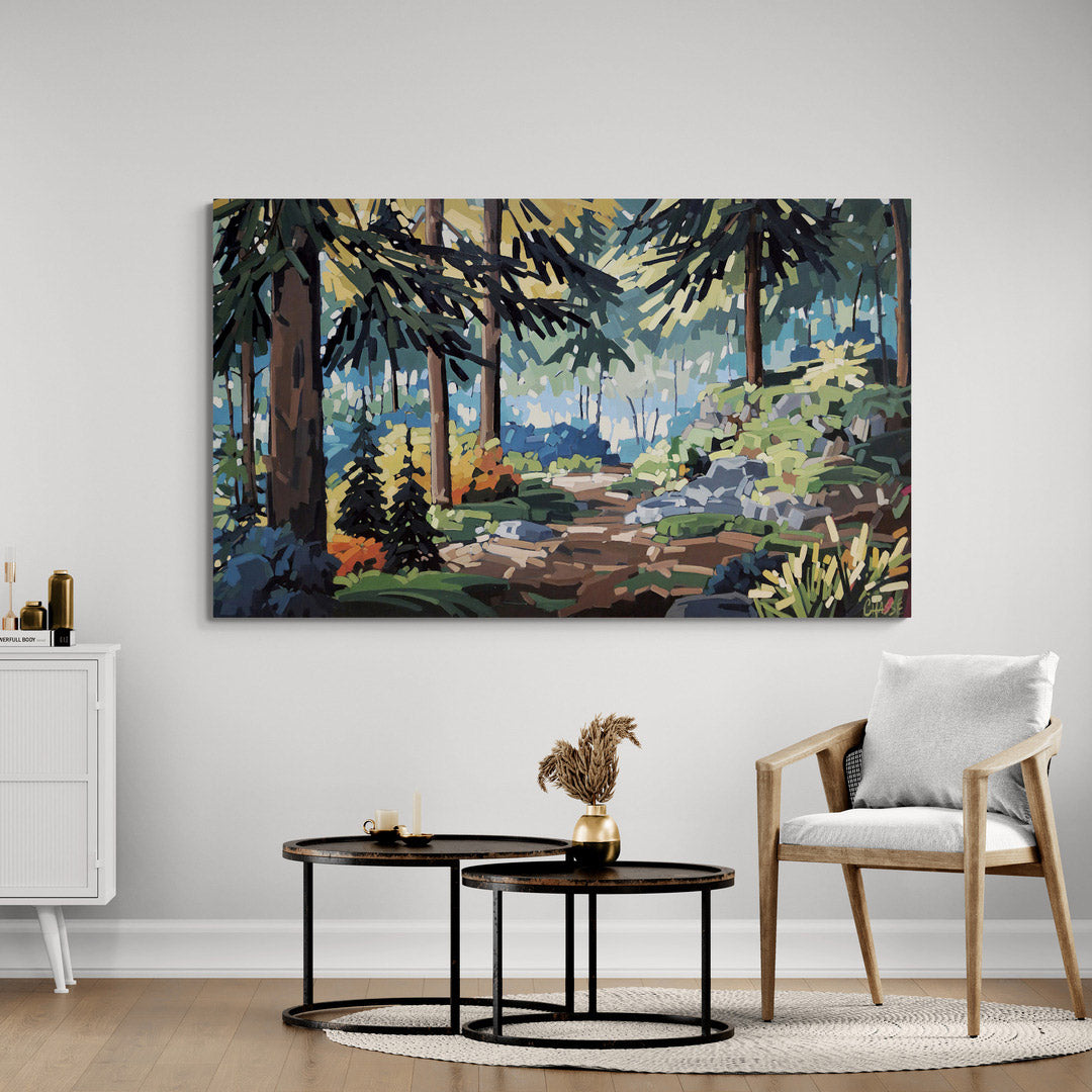 Grande peinture intitulée Marcher la forêt installée au-dessus d'une table basse dans un salon contemporain aux tons clairs. L'œuvre, représentant un sentier en forêt boréale baigné de lumière, s'intègre harmonieusement à un décor épuré composé de bois naturel, de blanc et de touches noires.