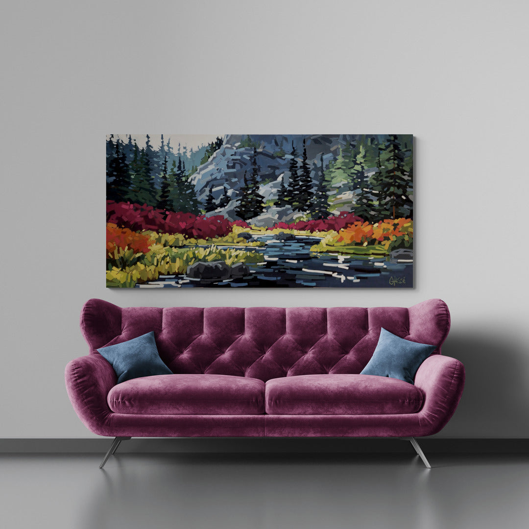 Un salon moderne avec un canapé en velours magenta, orné de deux coussins bleus. Au‑dessus, un grand tableau coloré représente un paysage stylisé avec une rivière, des arbres et des montagnes, peint en larges touches vives.